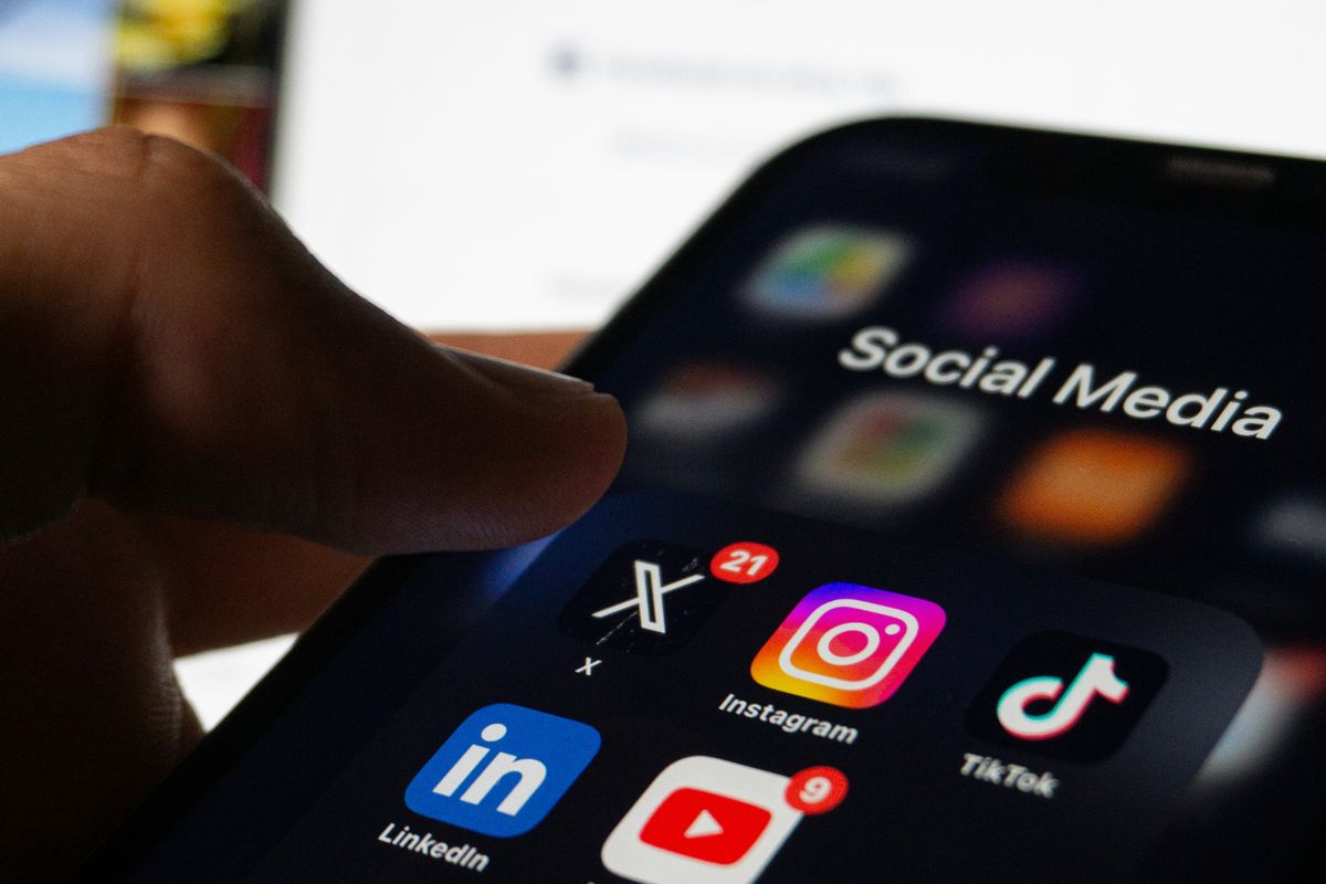 A person holding a smartphone with social media on the screen